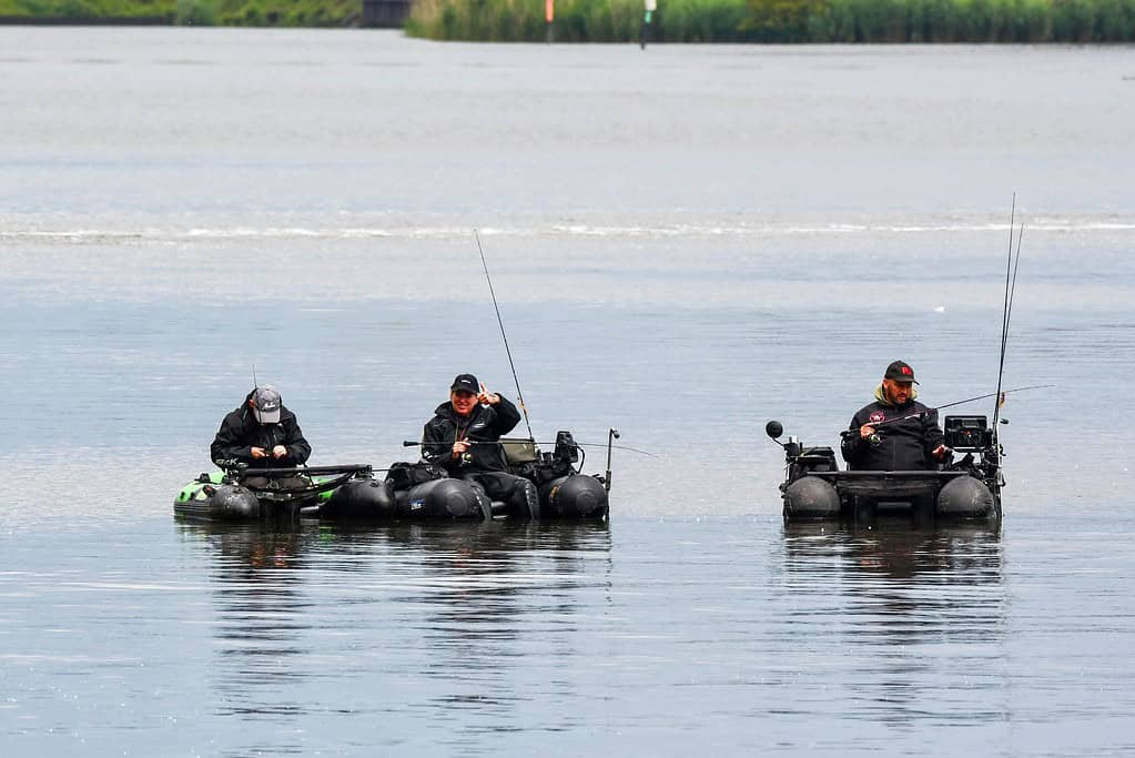 Drie mensen zitten in opblaasboten te vissen in kalm water. Ze gebruiken de laagdrempelige dropshottechniek om ongrijpbare vissen te vangen.