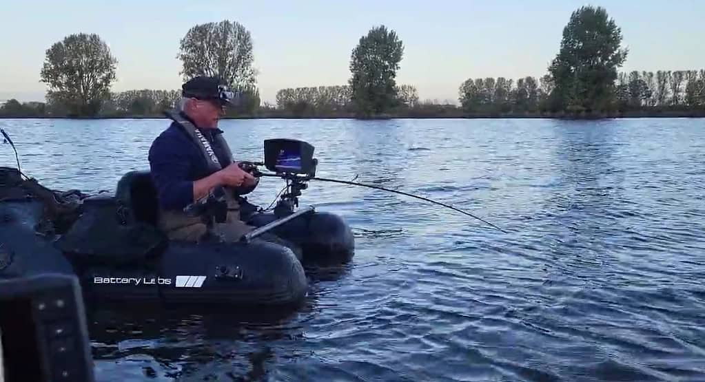 Een persoon die op een opblaasbaar vlot in een rivier zit te vissen, leert een belangrijke les over geduld terwijl hij wacht op een beet, met op de achtergrond zachtjes wuivende bomen.