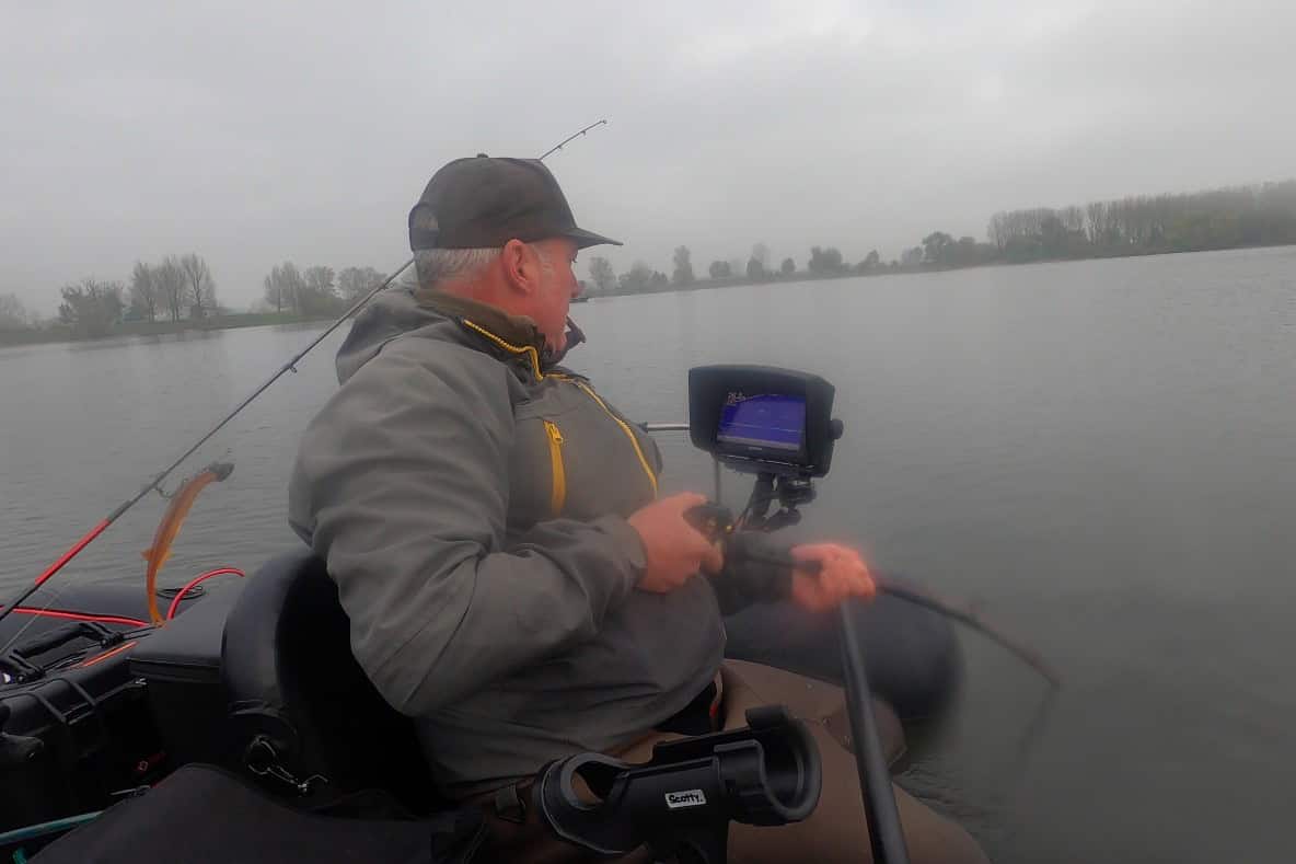 Iemand zit in een bootje te vissen op een meer, met een hengel en een fishfinder, en geniet van de serene rust van de bewolkte dag. Het is een geweldige afsluiting van wat een slechte week was geweest.