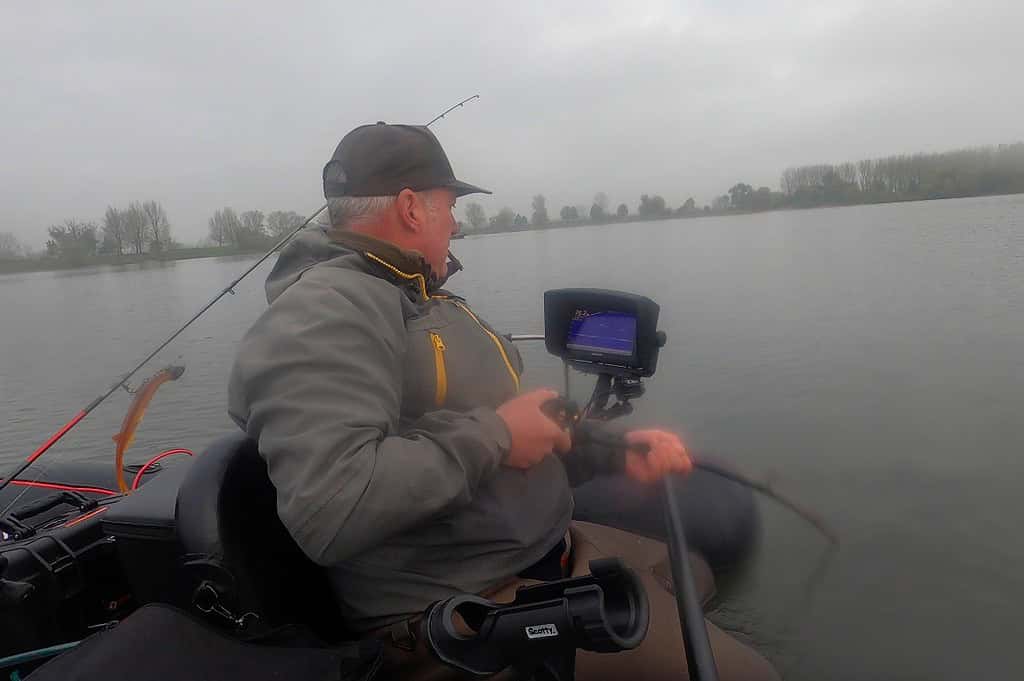 Op een kalm meer onder een bewolkte lucht, vist iemand vanuit een kleine boot, met hun hengel in de hand terwijl ze naar de fishfinder turen. Het is een slechte week geweest voor de vangsten, en ze hopen op meer geluk binnen twee meter van hun huidige plek.