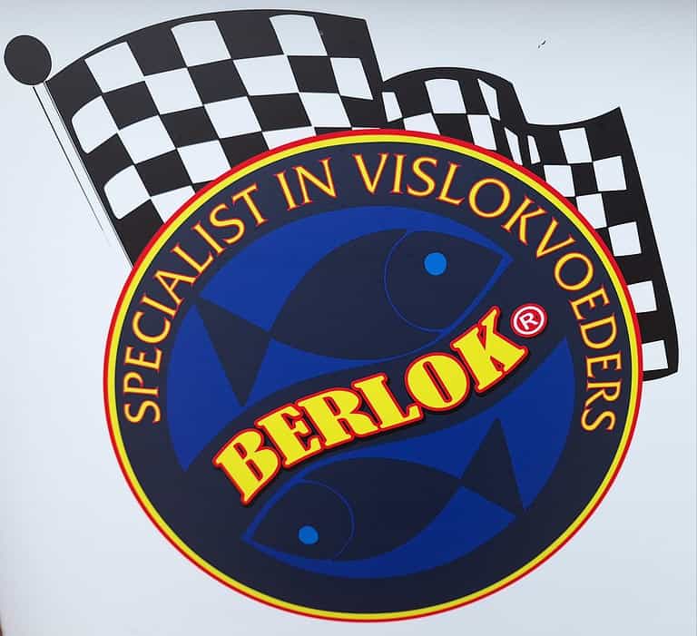 Logo met twee vissen in een cirkel. Tekst luidt "Specialist in Vislokvoeders" rond de cirkel en "Berlok" in vette letters. Een geblokte vlag en elementen van automatische concepten verheffen dit ontwerp.