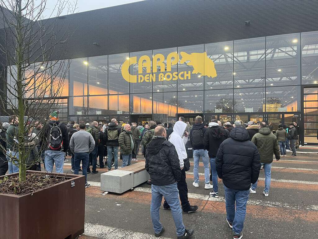 Buiten het gebouw met het opschrift "CARP DEN BOSCH" verzamelt zich een groep mensen die reikhalzend uitkijken naar de beurs van 2025.