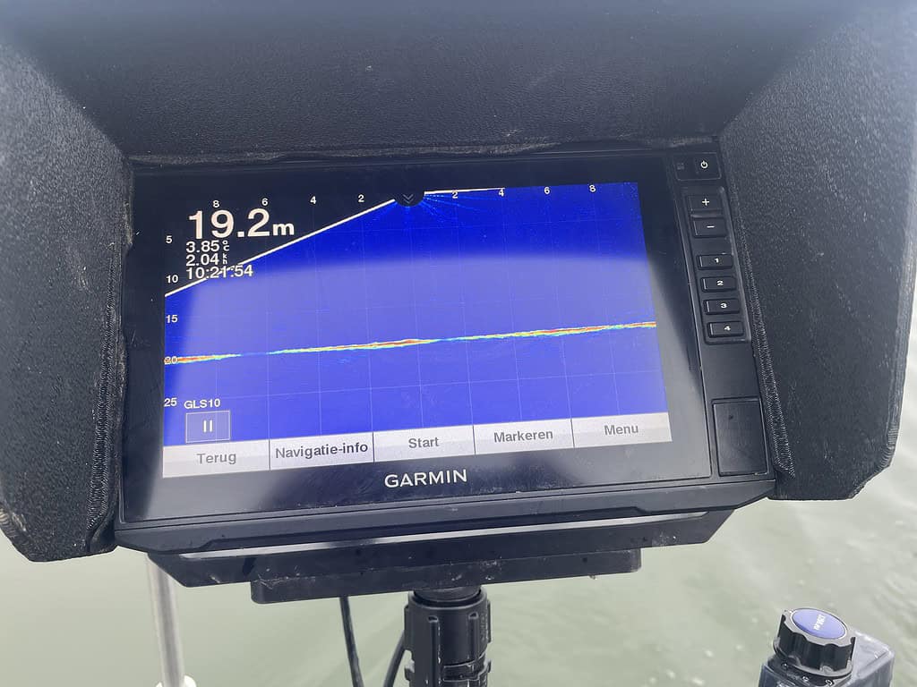 Close-up van een Garmin fishfinder display met een diepte van 19,2 meter. Het scherm toont grafieklijnen en navigatie-instellingen in het Nederlands.