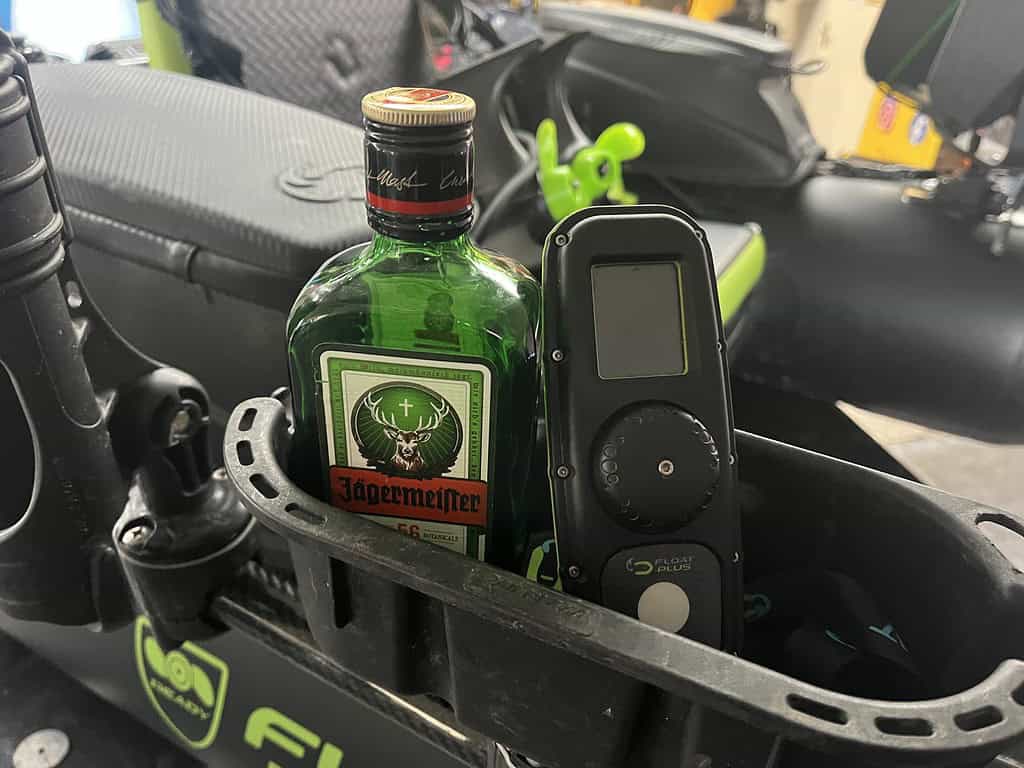 Een fles Jägermeister en een apparaat zitten netjes naast elkaar in een compartiment, net als de gezellige charme van de Bommelerwaard.