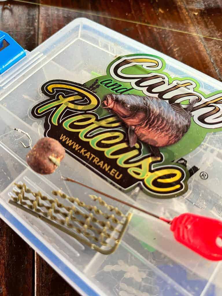 Een 'Catch and Release'-viskoffer met daarin een haak met aas, kleine accessoires en een rood gereedschap is perfect voor degenen die graag barbeel willen vangen.