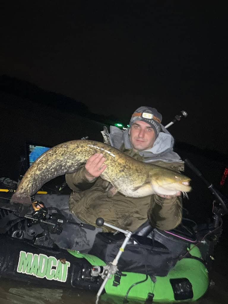 Een persoon die 's nachts een grote meerval vasthoudt, zit trots op een Madcat-opblaasboot. In deze bomvolle editie is dit een van de hoogtepunten van de week.
