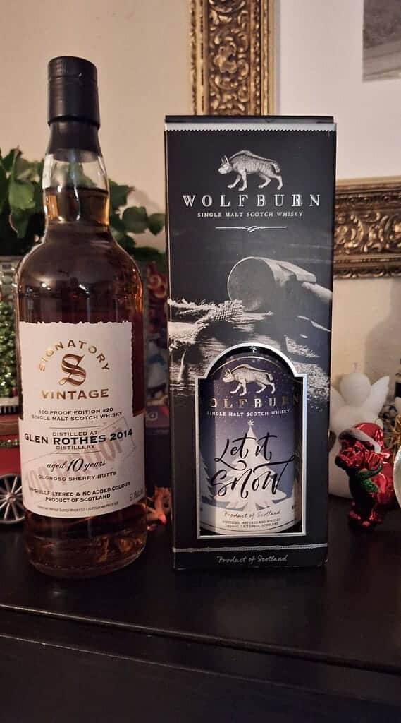 Flessen Signatory Vintage Glenrothes 2014 whisky en Wolfburn single malt scotch whisky staan elegant uitgestald op een tafel tegen een decoratieve achtergrond, ter ere van het vangsten-jaar in iets meer dan een week.