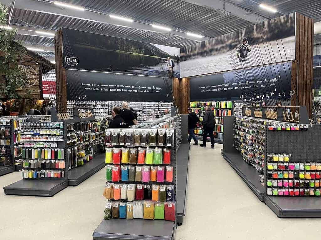 In de bruisende hengelsport megastore, staan de gangpaden vol met een caleidoscoop van levendige accessoires en benodigdheden. Enthousiaste klanten snuffelen onder de felle lichten en ontdekken alles van basis haken tot de geavanceerde Fauna 3.0 uitrusting in dit paradijs voor vissers.