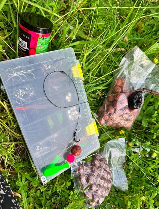 Een vastloodmontage is beaasd met pellets en ligt op een tacklebox